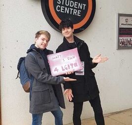 Image description: Matt, and their partner Daniel, campaigning to be elected LGBTQ+ Officers for York University Students' Union. They're holding a sign that says 